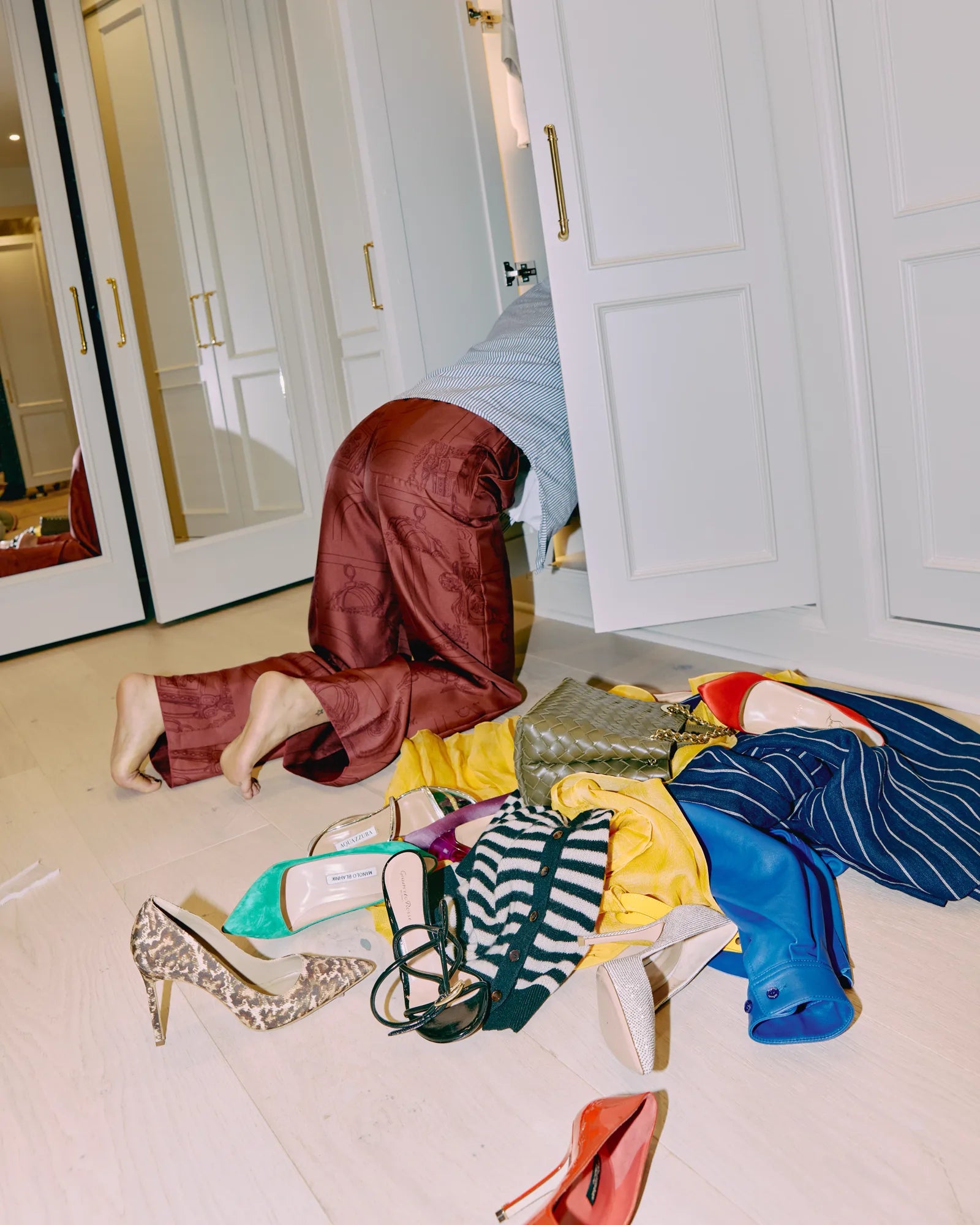 Open closet with a red dress and designer pieces spilled out on the floor