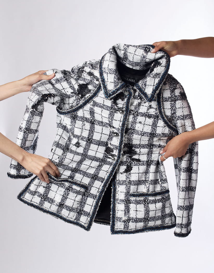 Hands holding up a Chanel tweed jacket